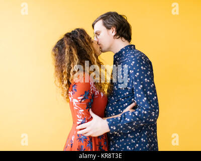 Couple kissing against yellow background Stock Photo