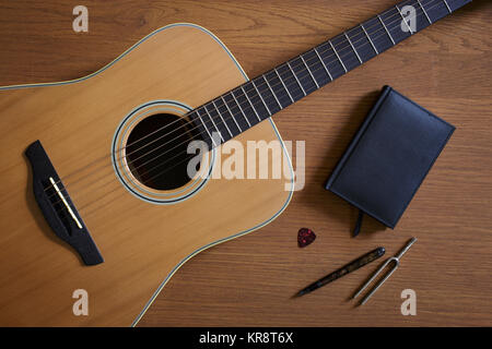 Acoustic guitar and tuning fork lying on floor Stock Photo