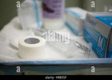 A tray of various medical equipment including a syringe of saline, tape, gauze, gloves and a bottle of barium sulphate solution Stock Photo