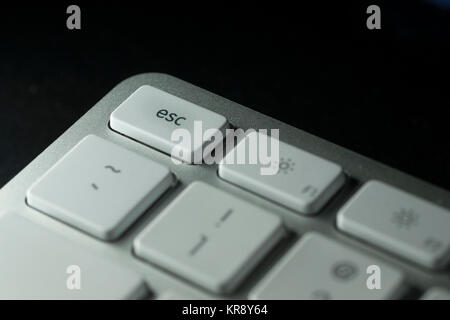 Closeup of escape key on computer keyboard with white keys on dark background Stock Photo