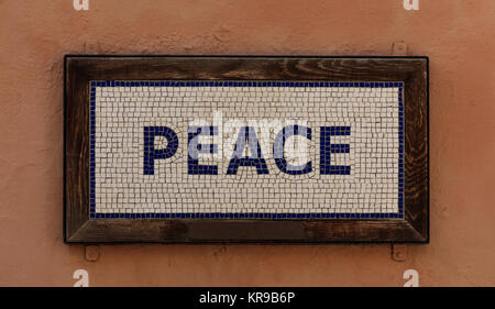 Word peace made from cubes. Mosaic pattern, wooden frame, salmon color background. Close up view. Stock Photo