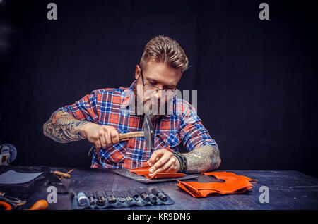Leather Worker cuts out leather goods in the workshop. Stock Photo