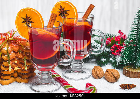 Christmas glass of red mulled wine on table with cinnamon sticks, branches of Christmas tree, snow, gingerbread, cone, candy, New Year decorations on  Stock Photo