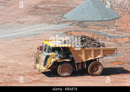 dumper truck carrying porphyry rocks through a quarry mine Stock Photo