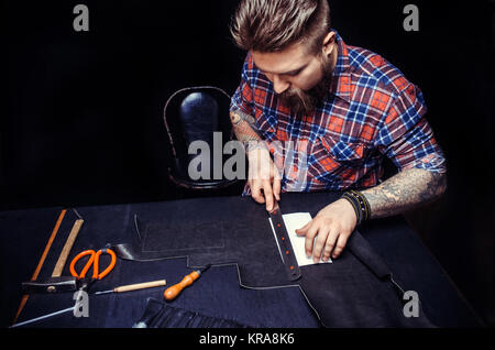Leather Currier creating new leatherwork in the work area./Currier of leather processes a workpiece from leather . Stock Photo