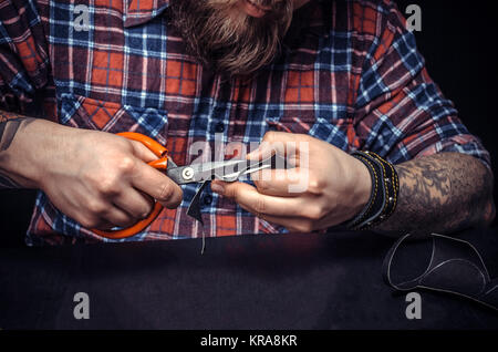 Leather Skinner producing leather goods at studio./Leather Professional focused on his work at his leather studio. Stock Photo