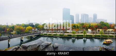 Osaka Castle Park canal with tourist boats and Gokurakubashi bridge panoramic misty autumn city scenery with Chuo-ku financial distric high-rise tower Stock Photo