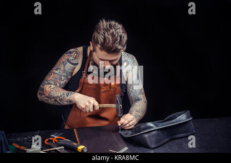 Leather Skinner working as artisan at the place of work./Artisan working with leather making quality products at workplace. Stock Photo
