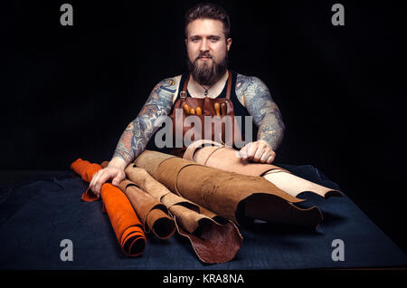 Handyman manufacturing new leather product./Professional Leather Worker producing leather workpiece at the desk. Stock Photo
