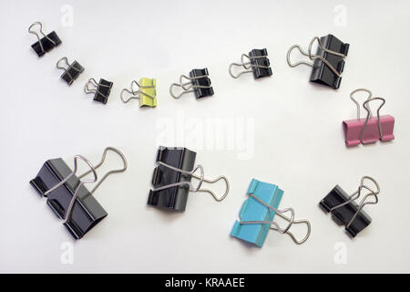 bunch of metal binder clips for paper, different sizes and colors. Laid in row Stock Photo