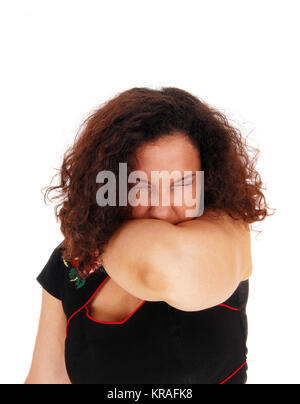 Sneezing woman with arm over mouth. Stock Photo