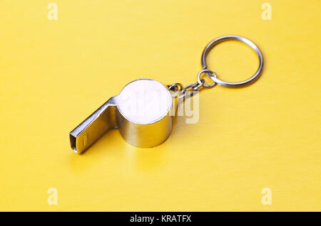 Sports or coaches metal whistle, closeup. Concept refereeing sport on yellow card background. Soccer or football referee whistle and caution cards Stock Photo