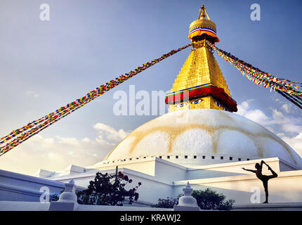Silhouette of man doing yoga natarajasana at Bodnath Great Buddhist Stupa with prayer flags in Kathmandu Stock Photo