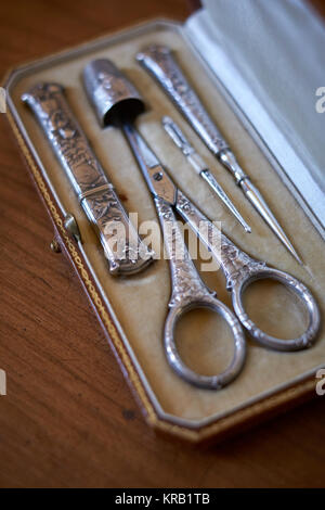 An antique vintage silver embroidery sewing set kit with scissors, thimble, threader, awl and needle case - minimal focus Stock Photo