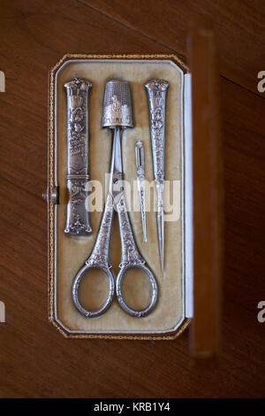 An antique vintage silver embroidery sewing set kit with scissors, thimble, threader, awl and needle case - overhead table top view Stock Photo