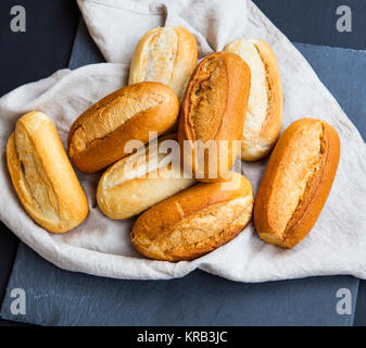 Freshly baked bread buns on a linen towel, whole bread buns heap with crust freshly oven baked Stock Photo