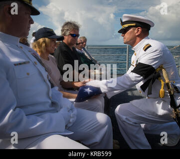 US Navy Captain Steve Shinego, commanding officer of the USS Philippine Sea (CG 58), presents the US flag to Carol Armstrong following the burial at sea service for her husband Apollo 11 astronaut Neil Armstrong, Friday, Sept. 14, 2012, aboard the USS Philippine Sea (CG 58) in the Atlantic Ocean. Armstrong, the first man to walk on the moon during the 1969 Apollo 11 mission, died Saturday, Aug. 25. He was 82. Photo Credit: (NASA/Bill Ingalls) Neil Armstrong burial at sea (201209140019HQ) Stock Photo