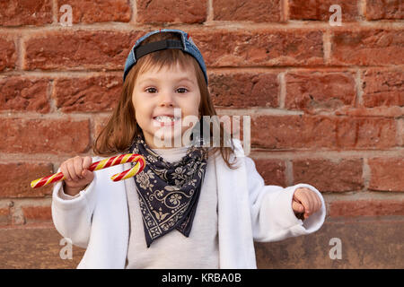 Beautiful cute child eating candies. portrait of cute little girl in the baseball cap Stock Photo