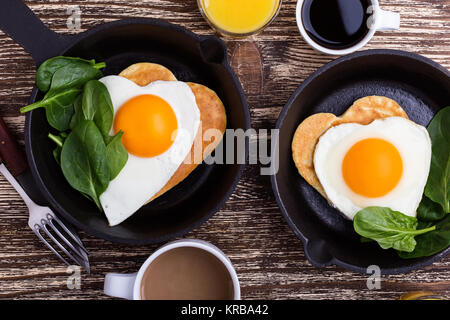 Valentine's day breakfast or brunch. Homemade  heart shape fried egg and pancake in cast iron skillet  with spinach, orange juice and cup of coffee. T