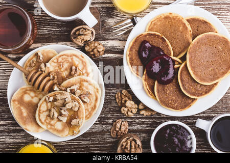 Pumpkin and buttermilk pancakes breakfast or brunch. Homemade   pancakes with berry jam, walnuts and honey, orange juice and cup of coffee. Table view Stock Photo