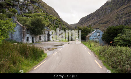 Ruined cottages beside the mountain pass road at Augher Lake in the Gap of Dunloe, nestled beneath the Macgillycuddy Reeks mountains in Ireland's Coun Stock Photo