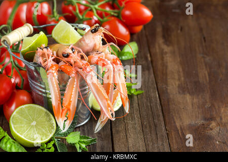 Raw langoustine in a bucket with vegetables Stock Photo