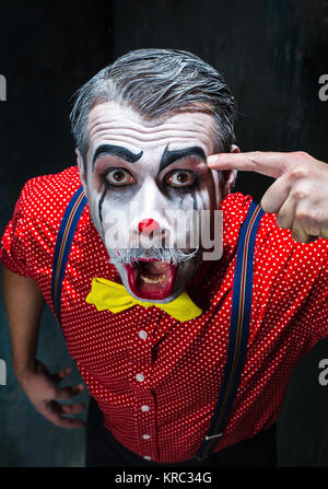 Terrible clown and Halloween theme: Crazy red clown in a shirt with suspenders Stock Photo