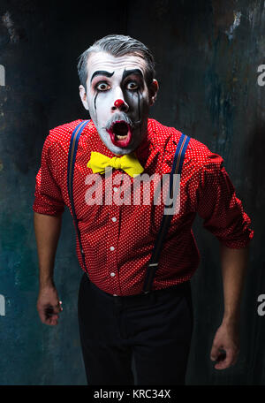 Terrible clown and Halloween theme: Crazy red clown in a shirt with suspenders Stock Photo