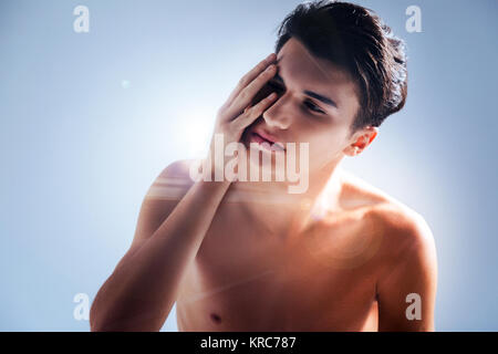 Pleasant young man touching his face Stock Photo