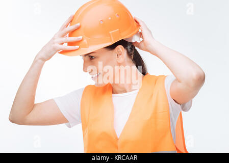 Charming female worker touching hard hat  Stock Photo