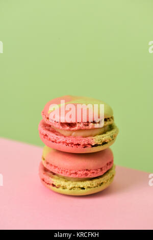 a pile of delicious pink and green macarons of mixed flavors on a pink and green background with a blank space on top Stock Photo