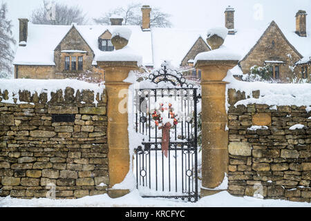 Christmas wreath on a gate in front of a cotswold stone house in december. Chipping Campden, Cotswolds, Gloucestershire, England Stock Photo