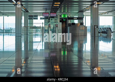 Departure gate at a modern airport with prohibited article screens above. Stock Photo