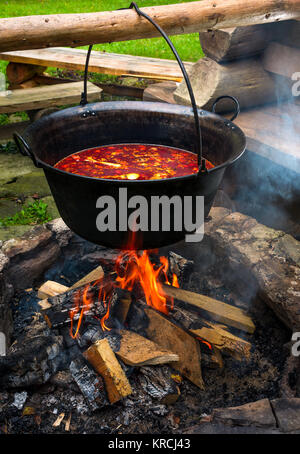 traditional Hungarian Goulash soup in cauldron. meal cooked outdoors on an open fire. delicious and healthy food popular in Central Europe Stock Photo