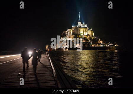 Le Mont Saint-Michel (Normandy, north-western France), 2015/03/22: Spring tide in the evening and walkers on the footbridge. (Not available for postca Stock Photo