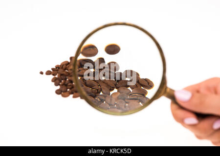Female hand keepig magnifying glass over the coffee beans Stock Photo