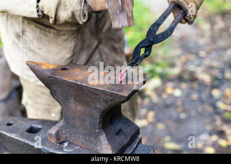 Blacksmith forges a buckle on anvil Stock Photo