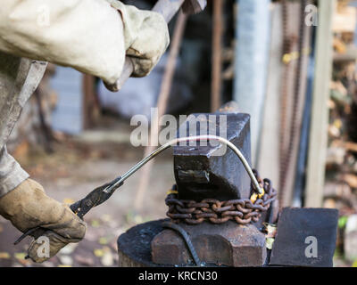 blacksmith forges iron rod on an anvil Stock Photo
