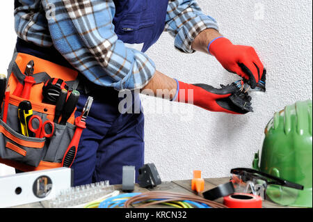 Electrician with hands protected by gloves and insulated tools works respecting the safety regulations in a residential electrical installation. Stock Photo