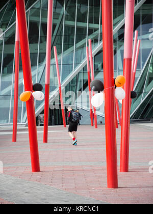 Dublin, Ireland - September 17, 2016: A pedestrian walks past sculptural poles and balloons outside Bord Gais Energy Theatre in Grand Canal Square in  Stock Photo
