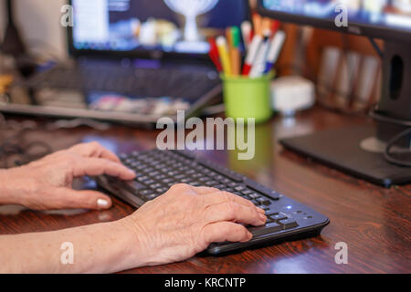 Hands of an elderly woman typing on a pc keyboard Stock Photo