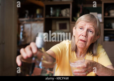Woman reaching for bottle of liquor Stock Photo