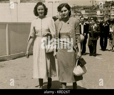Two female friends walking along the street while on holiday in Blackpool, Lancashire. Date: early 1950s