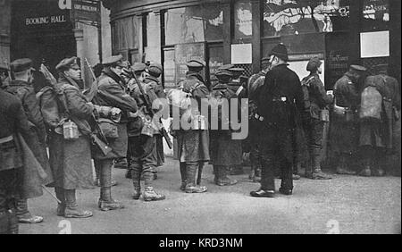 Troops just arrived at Waterloo Station from the trenches buying tickets at the booking office for travel to their suburban homes.  A typical scene at London train stations during the First World War.       Date: 1914
