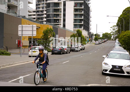 RHODES, SYDNEY, NEW SOUTH WALES, AUSTRALIA, 15 DECEMBER 2017: Woman cycling on the street of the modern suburb of Rhodes in Sydney, Australia. Stock Photo