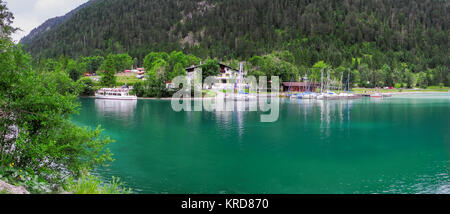 Panorama-Ansicht auf den Camplingplatz Seespitze, Hotel und Marina mit Ausflugsdampfer am Plan-See in Österreich vom gegenübeliegenden Ufer aus fotogr Stock Photo