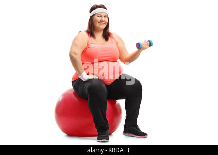 Overweight woman sitting on an exercise ball and exercising with a small dumbbell isolated on white background Stock Photo