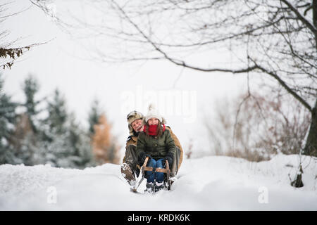 Grandfather and small girl sledging on a winter day. Stock Photo