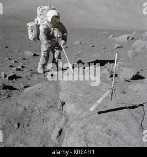 Scientist-astronaut Harrison Schmitt, Apollo 17 lunar module pilot, uses an adjustable sampling scoop to retrieve lunar samples during the second Apollo 17 Eextravehicular Activity EVA 2, at Station 5 at the Taurus-Littrow landing site.  A gnomon is atop the large rock in the foreground.  Image taken by Astronaut Eugene A. Cernan. Station 5, Sample 5060,5075,5080 taken during EVA 2 of the Apollo 17 mission. Original film magazine was labeled D film type was SO-368 Color Exterior CEX, Ektachrome MS, color reversal, 60mm lens with a sun elevation of 28 degrees.  NASA Identifier: as17-145-22157 F Stock Photo