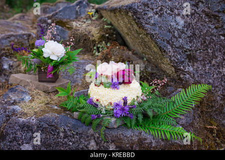 Wedding cake on river rock with native species plants and flowers at a North Umpqua River elopement wedding in Oregon. Stock Photo